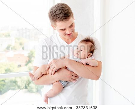 Father embracing infant near window