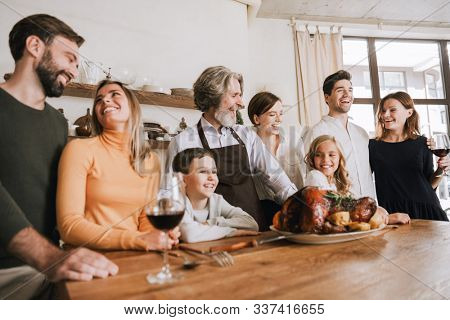 Smiling big family celebraring Christmas together, standing at the kitchen table