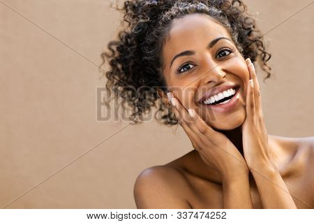 Beautiful young woman smiling after fantastic face treatment. Happy beauty african girl excited after spa treatment isolated on background with copy space. Surpise and astonishment beauty concept.