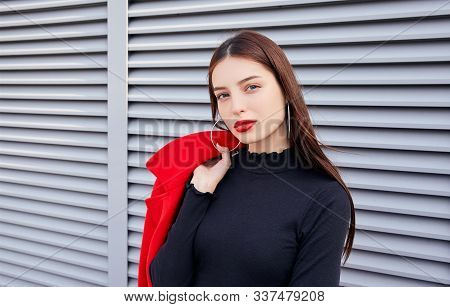 Magnetic Dishy Lady In Round Earrings, With Blue Eyes And Full Lips Stands On Gray Striped Backgroun