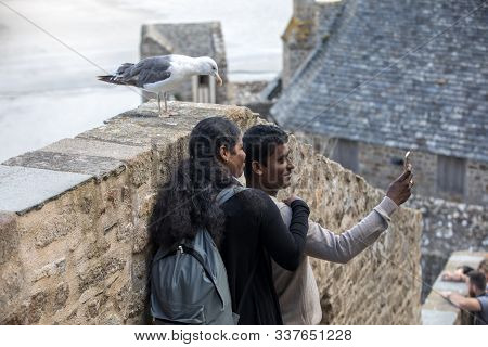 Le Mont-saint-michel, France - September 13, 2018: A Pair Of Hindus Take A Picture With A Seagull In