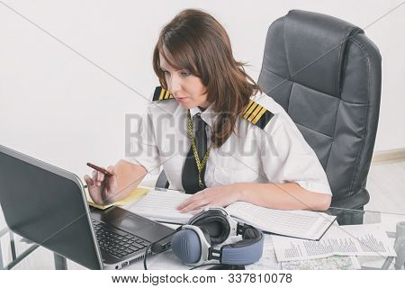 Beautiful woman pilot wearing uniform with epaulettes doing preflight briefing