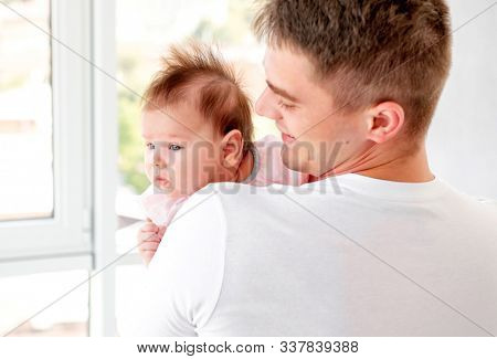 Father embracing infant near window