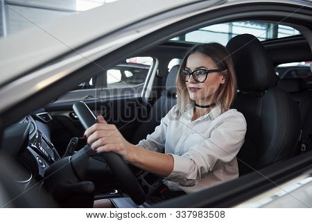 Beautiful Blonde Girl Sitting In The New Car With Modern Black Interior.