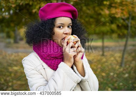 Portrait Of A Happy Youth. Dark-skinned Black Woman In Autumn Bites An Apple. Close-up, Smiling And 