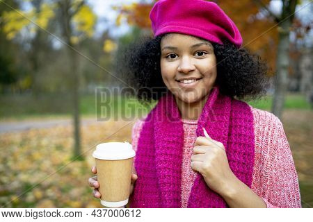 Portrait Of A Happy Youth. A Dark-skinned Black Woman In An Autumn Park Holds A Glass Of Glass Coffe