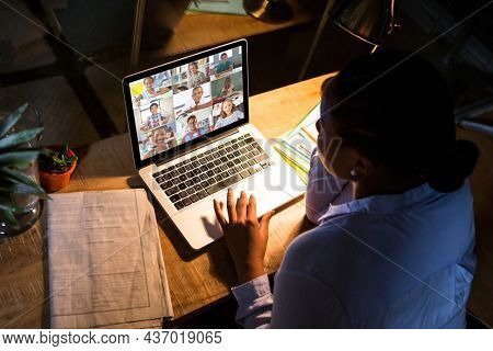 African american woman using laptop for video call, with diverse elementary school pupils on screen. communication technology and online education, digital composite image.