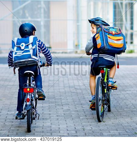 Two School Kid Boys In Safety Helmet Riding With Bike In The City With Backpacks. Happy Children In 