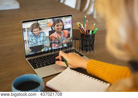 Caucasian woman using laptop for video call, with diverse elementary school pupils on screen. communication technology and online education, digital composite image.