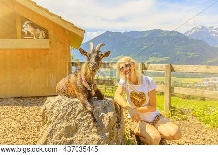 Tourist Girl Playing With A Goat In Maienfeld Village. Deutch Switzerland Of Graubunden Canton Or Gr