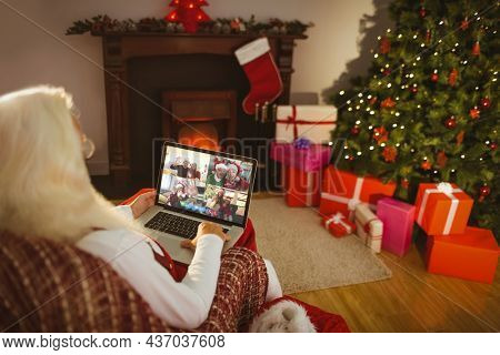 Caucasian santa claus on christmas laptop video call with diverse group of friends. christmas, festivity and communication technology.