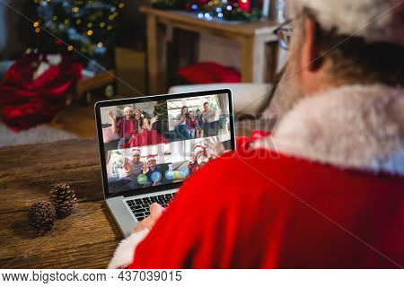 Caucasian santa claus on christmas laptop video call with diverse group of friends. christmas, festivity and communication technology.