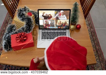Caucasian woman on christmas laptop video call with diverse group of friends. christmas, festivity and communication technology.