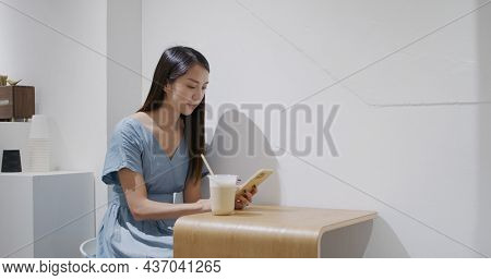 Woman enjoy her coffee and use mobile phone inside cafe