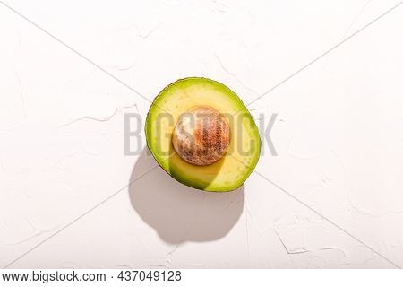 Half Cut Of Fresh Ripe Avocado On White Concrete Background From Above With Hard Shadows, Top View