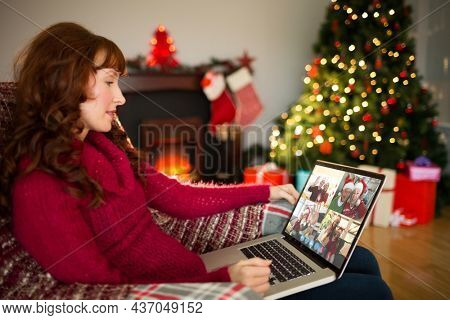 Caucasian woman on christmas laptop video call with diverse group of friends. christmas, festivity and communication technology.