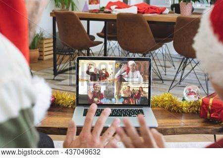 Caucasian couple on christmas laptop video call with diverse group of friends. christmas, festivity and communication technology.