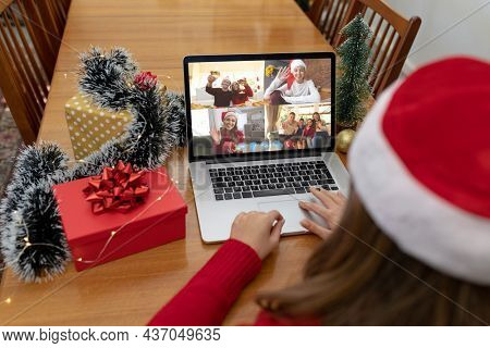 Caucasian woman on christmas laptop video call with diverse group of friends. christmas, festivity and communication technology.