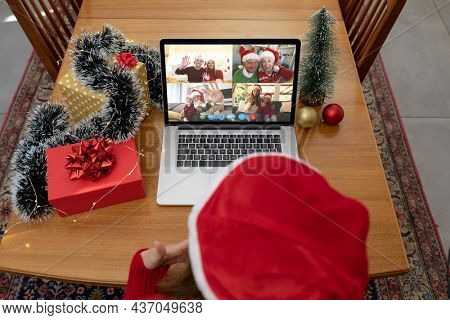 Caucasian woman on christmas laptop video call with diverse group of friends. christmas, festivity and communication technology.