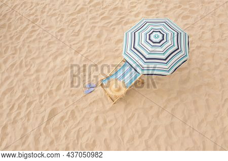 Striped Beach Umbrella Near Sunbed With Vacationist's Stuff On Sandy Coast, Aerial View