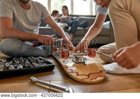 Crop Close Up Of Caucasian Dad And Teen Son Repair Skateboard With Toolset Utensils On Family Home W