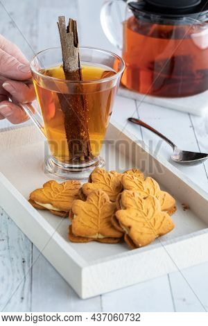Pumpkin Cookies On A Tray With A Hand Holding A Cup Of Cinnamon Tea.