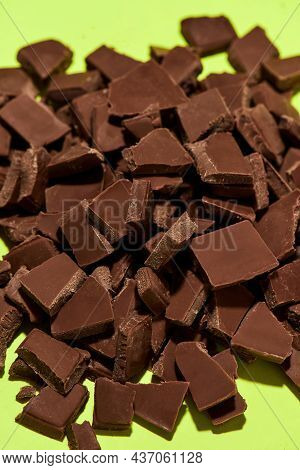 Closeup Of Broken, Crushed Dark Chocolate Bars Stack Isolated Over Green Background. Sweet Junk Food