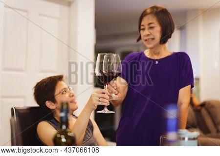 Smiling Woman Feeling Happy While Having Glass Of Red Wine With Her Mother.