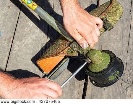 Close-up Of Unscrewing The Screw On The Trimmer Gearbox For Mowing Grass With A Special Key. Equipme