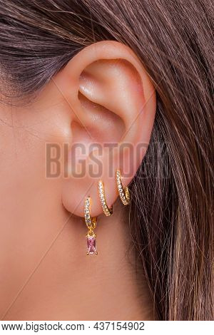 Woman Ear With Mulriple Piercings Wearing Beautiful Earrings With Zirconia- Details Capture