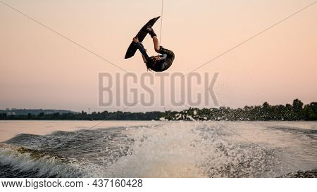 Male Wakeboarder Masterfully Jumping And Flips On Wakeboard Over Splashing Wave