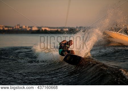 Dynamic View Of The Waves Splashing And Male Wakeboarder Trying To Stand On It