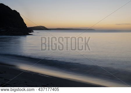 Beautiful Sunrise Over Pentewan Sands In Cornwall With Pastel Sky And Long Exposure Ocean