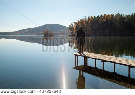 A Man Admires The Landscape Of A Mountain Lake While Standing On The Pier