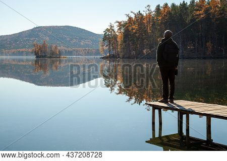 A Man Admires The Landscape Of A Mountain Lake While Standing On The Pier
