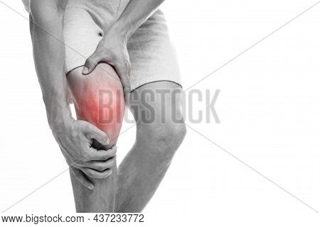 Cropped Young European Man Suffering From Knee Pain, Presses Hand To Sore Spot, Highlighted In Red, 