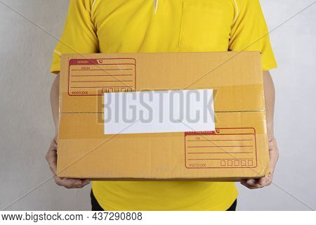 Closeup Hands Of Delivery Man Holding Package To Deliver. Courier Hand Holding Brown Box Isolated On
