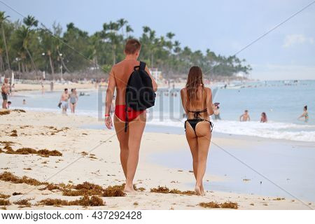Vacation On Tropical Beach, Couple Walking By The Sand On Coconut Palm Trees Background. Sargasso Se