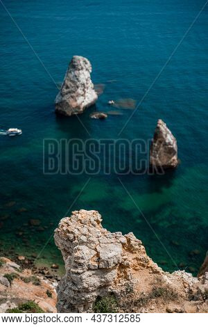 Two Rocks Stick Out Of The Water In The Middle Of The Turquoise Sea. Scenic Ocean View. Speed Boat S
