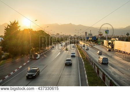 Antalya, Turkey - November 28, 2020: Busy traffic road in Antalya city at sunset, Turkey. Antalya cityscape with magnificent mountains at background.