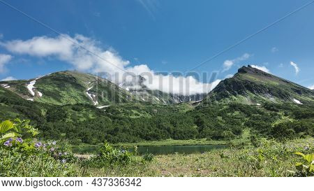 A Picturesque Mountain Range Against The Blue Sky. There Are Patches Of Snow On The Slopes. At The F