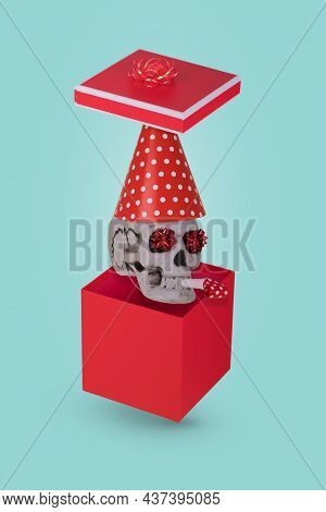 Human Skull With A Red Birthday Cap And Whistle Coming Out Of The Gift Box Isolated On A Bright Blue