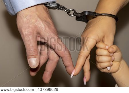 Male And Female Hands Are Handcuffed. The Child\'s Hand Is Holding On To The Mother\'s Finger, Selec