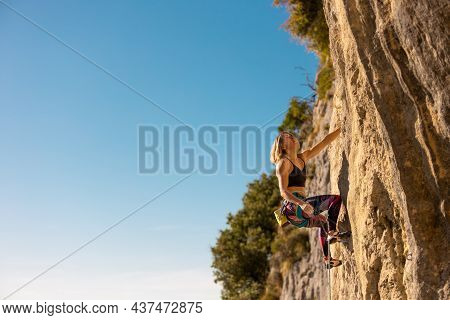 The Girl Climbs The Rock. The Climber Trains On Natural Terrain.  A Woman Overcomes A Difficult Clim