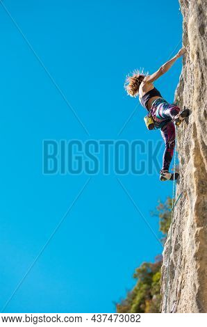 The Girl Climbs The Rock. The Climber Trains On Natural Terrain.  A Woman Overcomes A Difficult Clim