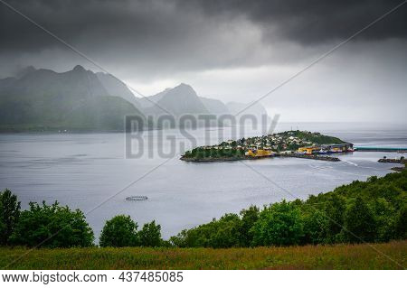 Husoy Fishing Village On The Senja Island In Norway With Mountains In The Background. The Village Co