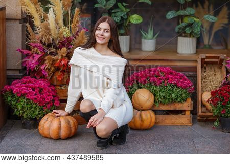 Beautiful Smiling Model With Orange Pumpkins Portrait. Fashionable Beautiful Young Girl In White Dre