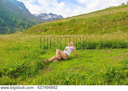 Happy Carefree Woman With A Short Skirt Sitting In The Countryside Of Guarda Village Of Scuol In Swi