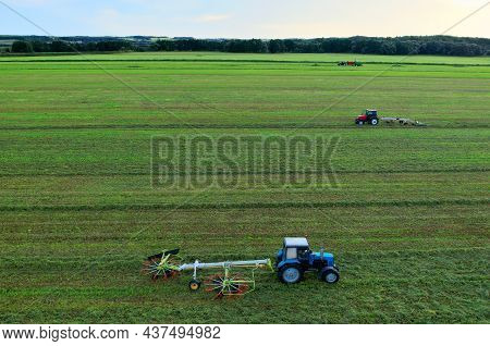 Tractor Raking Grass For Silage Harvesting. Agriculture Machinery Working At Field. Grass Silage For