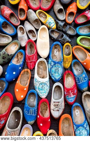 Background - Old wooden Dutch shoes - klomps. A lot of colorful old clomps against the background of a wooden wall. Popular souvenirs. Traditions of Holland. 